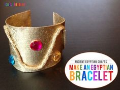 a gold cuff with an egyptian or egyptian symbol on it and a red jewel in the middle