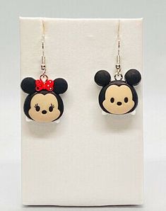 a pair of mickey mouse earrings with a red bow