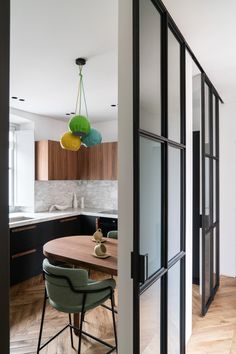 an open door leading to a kitchen with wooden floors and black cabinetry on the walls