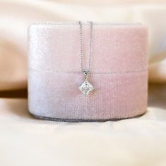 a pink velvet box with a diamond pendant on it