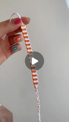 a hand holding an orange and white string with a small triangle on it's end