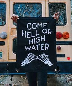 a woman holding up a sign that says come hell or high water