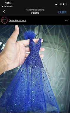 a hand holding a blue dress made out of sequins