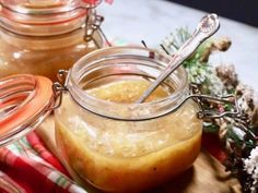 two jars filled with liquid sitting on top of a wooden cutting board next to pine cones