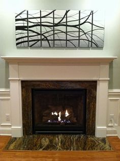 a fire place with a painting on the wall above it