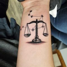 a woman's arm with a tattoo on it that has an image of a balance scale