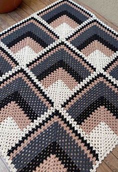 a black, white and pink rug sitting on top of a wooden floor next to a potted plant