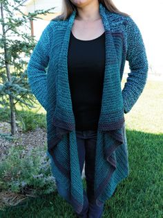 a woman standing in the grass with her hands on her hips, wearing a blue knitted cardigan