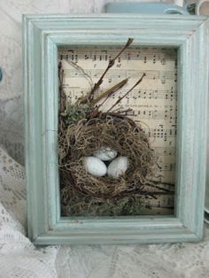 a bird's nest with three white eggs in it on top of sheet music