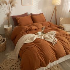 a bed with an orange comforter and pillows