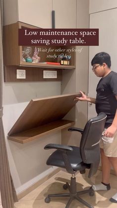 a man standing next to a desk with a chair on it and a shelf above the desk