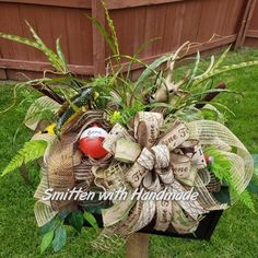 an image of a wreath made out of newspaper strips and ribbons on the grass with words smitten with handmade