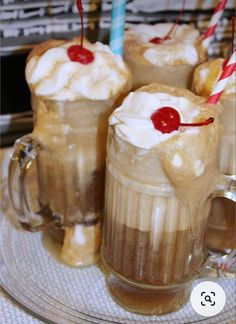 three glasses filled with ice cream and topped with cherries on a glass platter