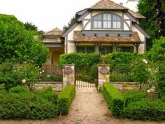 a large house surrounded by lush green trees and bushes with a stone pathway leading to the front door