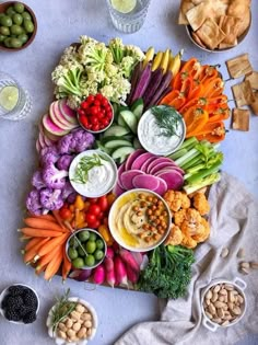 a table topped with lots of different types of vegetables and dipping sauces on top of it