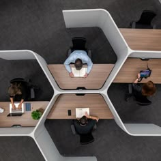 an overhead view of three people working at desks in the same cubicle area