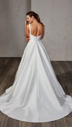 a woman in a white wedding dress standing on a wooden floor with her back to the camera