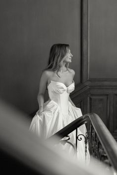 black and white photograph of a woman in a wedding dress walking down the stairs with her hand on her hip