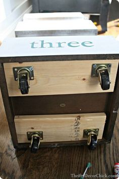 a wooden box with two drawers on top and the word three painted on it's side