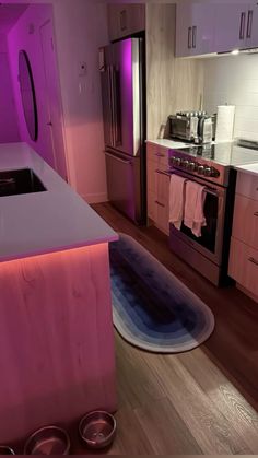 a kitchen with purple lighting and stainless steel appliances