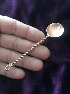 a person holding a spoon in their hand with a chain attached to the end of it