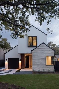 a modern house with white brick and black shutters on the front, surrounded by green grass