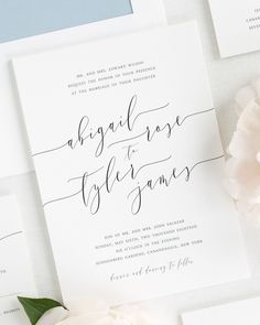 the wedding stationery is laid out on top of each other, with flowers in front