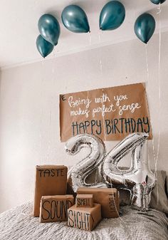 some balloons are hanging from the ceiling above a bed with a sign that says happy birthday