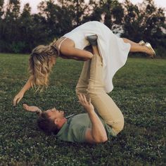 a man and woman are playing in the grass with their feet on each other's shoulders