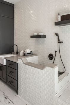 a bathroom with white tile and gray cabinets