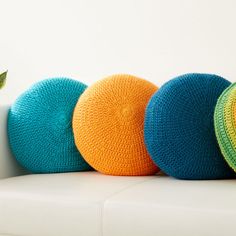 three crocheted balls sitting on top of a white couch next to a plant