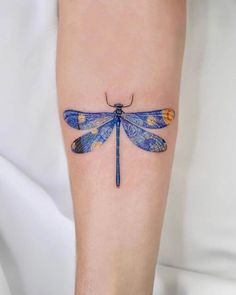 a blue and yellow dragonfly tattoo on the right leg, with an orange spot