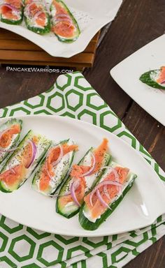 several slices of cucumber and tomato on a white platter with green napkins