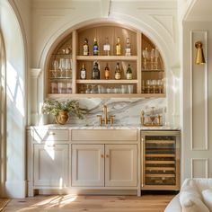 a kitchen filled with lots of bottles and glasses on top of a wooden cabinet next to a sink