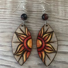 a pair of earrings with wood and beads on them sitting on top of a wooden table