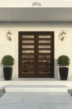 two potted plants are sitting in front of the entrance to a building with glass doors