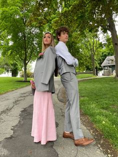 a man and woman standing next to each other on a sidewalk with trees in the background