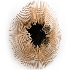 a circular object made out of bamboo sticks on a white surface with a black center piece in the middle