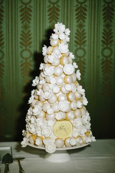 a white and gold wedding cake with flowers on the top is surrounded by silverware