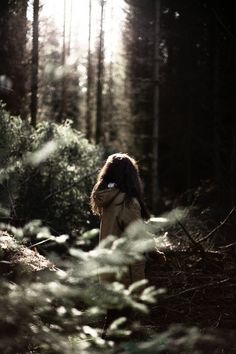 a woman standing in the middle of a forest