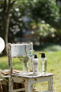 a white chair sitting on top of a lush green field next to a bottle of lotion