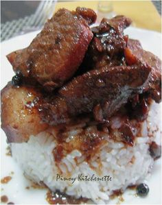 a white plate topped with rice covered in meat and gravy on top of it