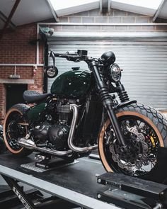 a black motorcycle parked on top of a wooden table next to a metal garage door