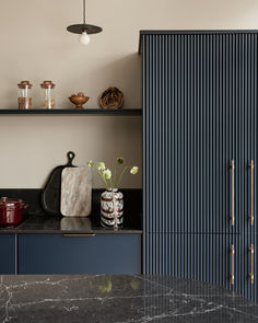 a kitchen with marble counter tops and blue cabinets, along with brass pulls on the doors