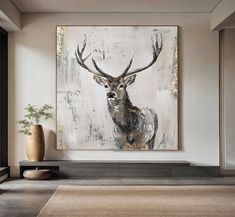 a deer painting hanging on the wall next to a vase and plant in a living room