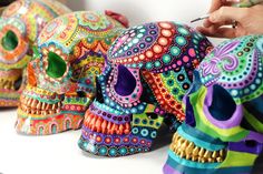 a person is drawing on some colorful skulls