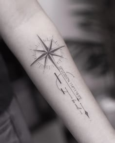 a person's arm with a compass tattoo on the forearm and an arrow in the middle