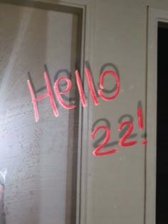 the reflection of someone holding a cell phone in front of a door with writing on it