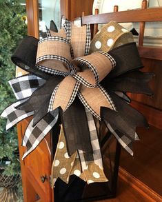 a black and white bow with polka dots hanging from a wooden chair in front of a christmas tree