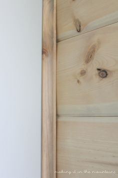 an open door with wood planks on the side and white walls in the background